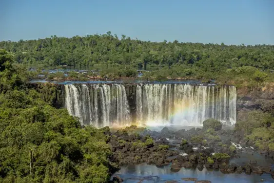 Quedas das Cataratas do Iguaçu cercadas de mata, com um arco-íris na base