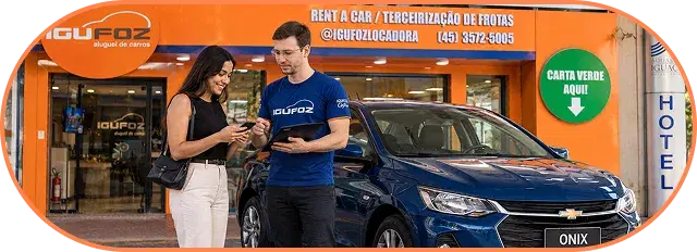 Atendente da IguFoz entregando as chaves de um carro a clientes na frente da loja
